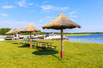 Beach umbrellas on green lawn in Pisz sailing port on Lake Ros on summer sunny,  Masurian Lakes, Poland