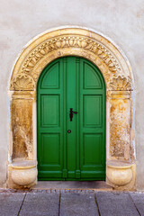 Green door inserted into an old Arch framed with Ornament