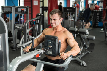 Muscular man working out in gym doing exercises, strong male