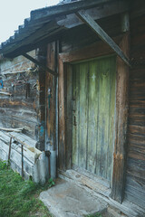 An old abandoned wooden building in a village manor. A structure made of cracked, sun-burned logs.