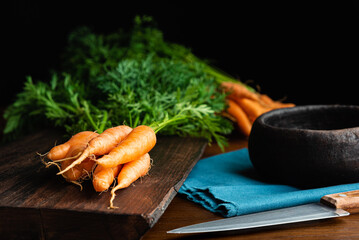 Fresh raw organic carrots with branch over a wood cutting board