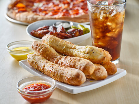 Garlic Butter Breadsticks With Soda And Pizza In Background