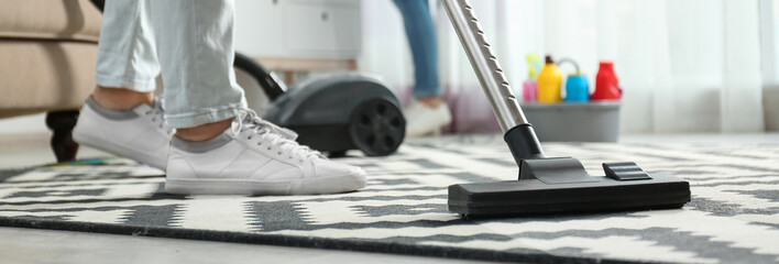 Cleaning service worker vacuuming carpet indoors, closeup. Banner design