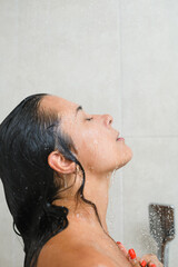 Brunette woman wash hair under water drops