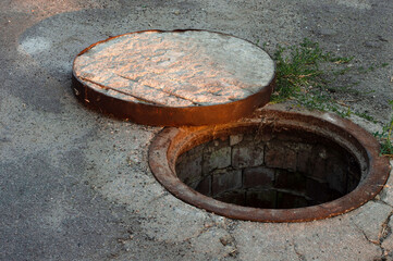 A view from above of a dangerous open sewer hatch, a danger for people who walk along the street in...