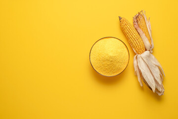 Corn flour in a bowl isolated on yellow background. Top view with polenta