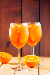 Aperol spritz cocktail on a wooden background. Two glasses of aperol spritz with orange slised. Summer cocktail in glass. Trendy drink. Rustic style