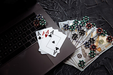 Online poker casino theme. Gambling chips and playing cards on laptop.