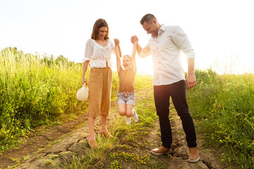 Happy parents and kid walking together in summer