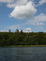 Obraz premium Lake in Przywidz, Poland - green trees and a big white cloud on the blue sky