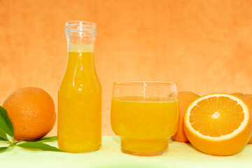 Frasco de cristal con zumo de naranja natural y fruta fresca sobre una mesa