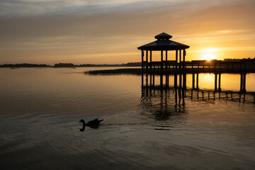 Fototapeta na wymiar Sunrise over a gazebo at a small lake in a central Florida retirement community