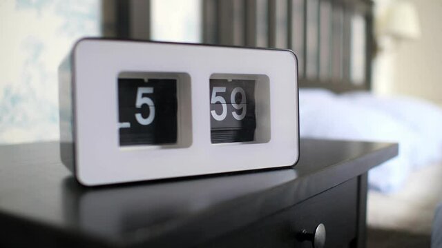 flip clock in white case shows one minute to 6 pm on table