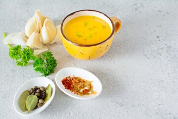 Homemade chicken (bone) broth/bouillon with vegetables, spices and herbs in a bowl (cup) on a light background. Natural collagen of animal origin. Liquid broth from meat, fish, vegetables.