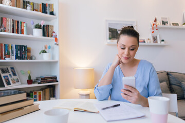 Young woman working at home and using mobile phone