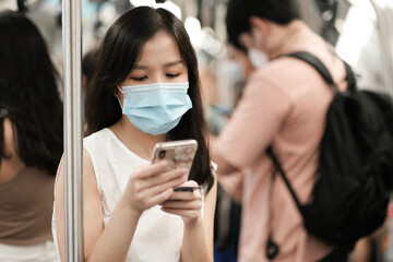 Fototapeta na wymiar Asian girl wear surgical mask to protect the Covid-19 virus in sky train, New normal lifestyle