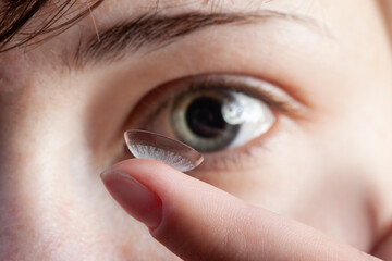 Girl with a contact lens on her finger (focus on the lens)