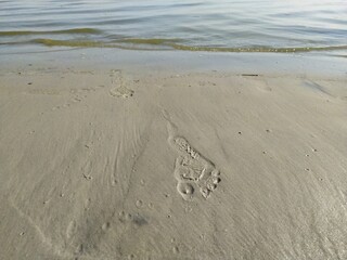 The footprint of a bare foot on the sand on the beach