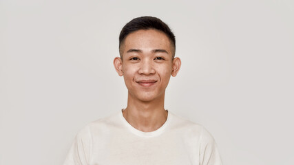 Young guy. Portrait of young asian man with clean shaven face smiling at camera isolated over white background. Beauty, skincare, health concept