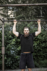 Fototapeta premium Young man doing pull-up on horizontal bar. Man fitness at the stadium