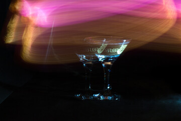 Glass of cocktail in a dark room and neon light trails