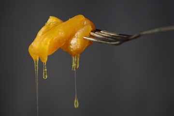 Traditional South African Afrikaaner dessert.  Koeksister on a silver fork dripping in honey