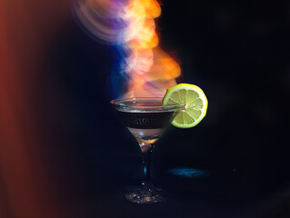 Glass of cocktail in a dark room and neon light trails