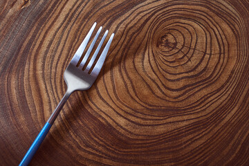 The silver fork lies on a slice of a tree. wooden table. With copy space.