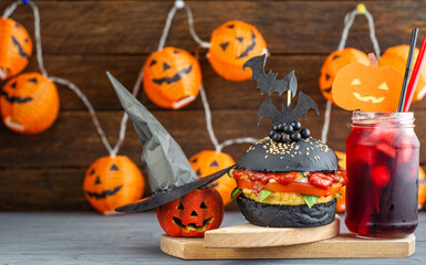 Halloween Spooky Black Burger with Cheese. Cheeseburger on Halloween pumpkin head jack lantern background