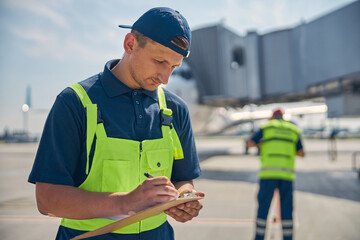 Serious aircraft technician filling out a form