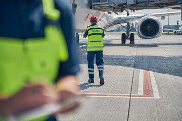 Man in the safety overalls in front of a plane