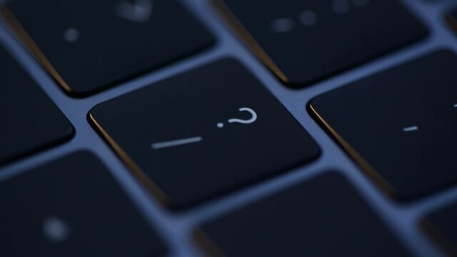 Finger single press question button at night on backlit keyboard. Search for an answer on the web. People have a lot of questions. Cinematic footage of grey modern laptop
