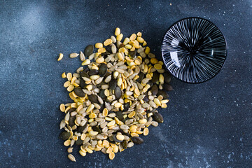 Sunflower and pumpkin seeds in bowl on the blue background. Large group of seeds. Snack and appetizer.