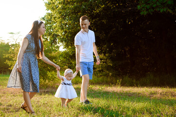 Fototapeta premium Happy family at sunset. Father, mother and child daughter having fun and playing.