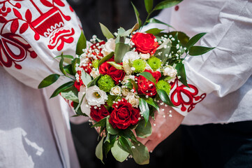 Newlyweds are holding a wedding bouquet of white and red roses