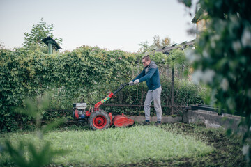Obraz premium A man works in the garden, plows the soil with a cultivator