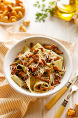 Pappardelle pasta with chanterelle mushroom and fresh parsley sprinkled with grated Parmesan cheese top view