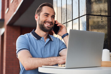 Cheerful handsome man with gadgets in cafe outdoors