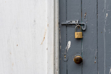 Painted old wooden door bolted shut and locked with a padlock