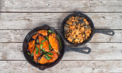 Vietnamese simmered salmon in cast iron pan on a wooden table