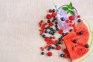 milkshake smoothies with fresh currant berries, raspberries, watermelon slices and mint leaves on linen textiles