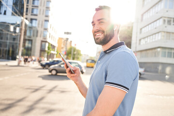 Smiling bearded man walking with smartphone in hands