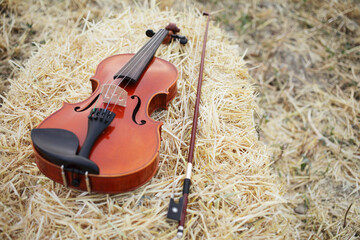 One violin and bow placed on a pile of straw in the field. Music Violin training