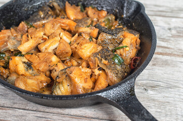 Vietnamese simmered salmon in cast iron pan on a wooden table