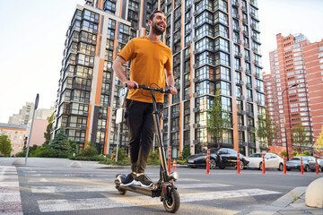 Happy bearded man commuting through city on scooter