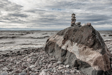 Fototapeta premium Beautiful natural stones that are stacked on a large rock by the Swedish Baltic Sea on an empty pebble beach