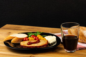 Classic meatloaf, cherry tomatoes, mozzarella, parsley, white bread in a black plate on a wooden background. Glass of pomegranate juice