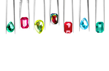 Set of tweezers with different shiny gemstones on white background