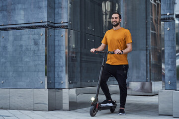 Cheerful handsome guy using eco transport in city