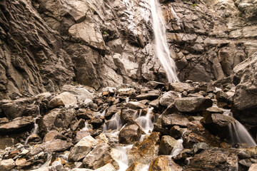 Water flows over rocks at the bottom of a mountain waterfall.